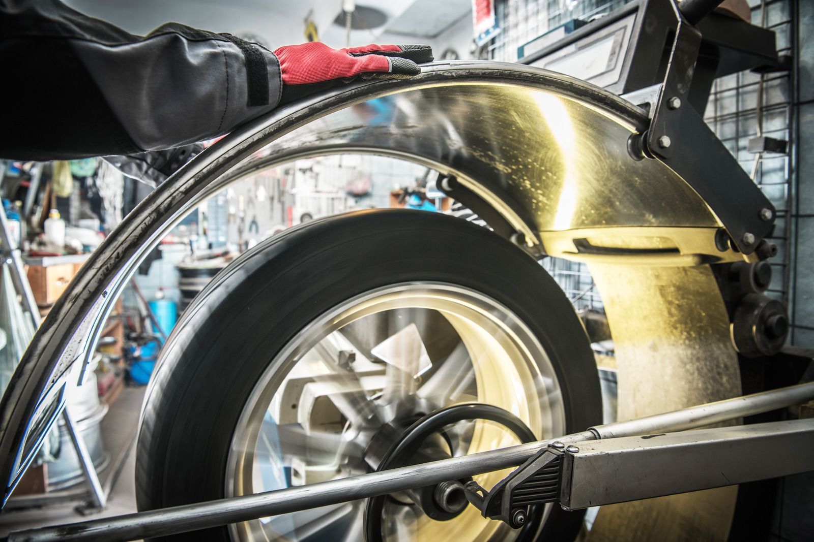 A person is balancing a tire on a machine in a garage.