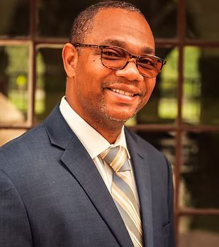A man in a suit and tie is smiling for the camera.