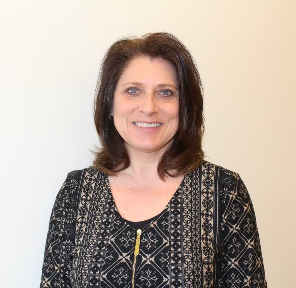 A woman wearing glasses and a black shirt smiles for the camera