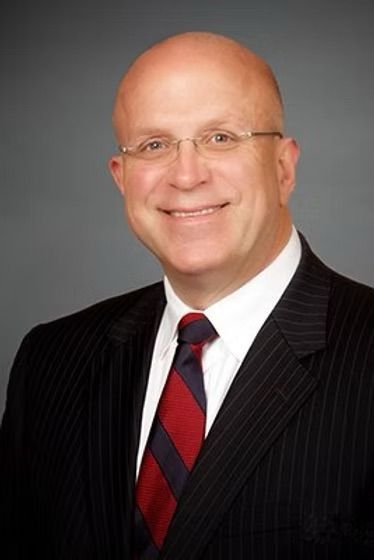 A man in a suit and tie is smiling for the camera
