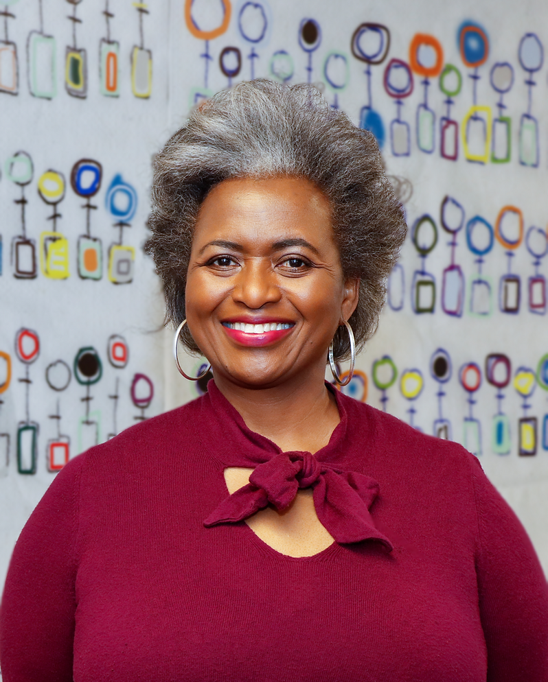 A woman with gray hair is smiling in front of a wall of women 's symbols