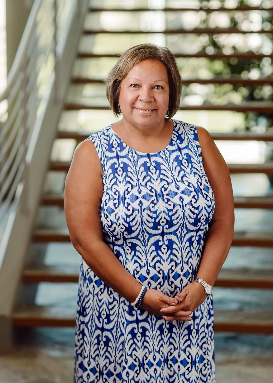 A woman in a blue and white dress is standing on a set of stairs.