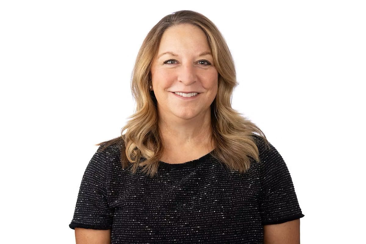 A woman in a black top is smiling for the camera.