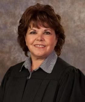 A woman in a judge 's robe is smiling for the camera