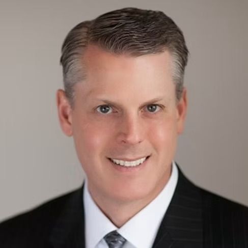 A man in a suit and tie is smiling for the camera.