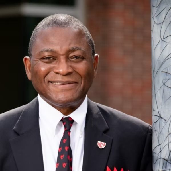A man in a suit and tie with a shield on his jacket