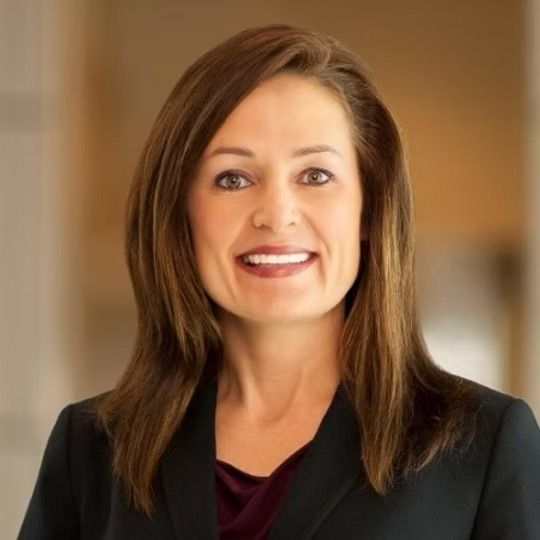 A woman in a black suit is smiling for the camera.