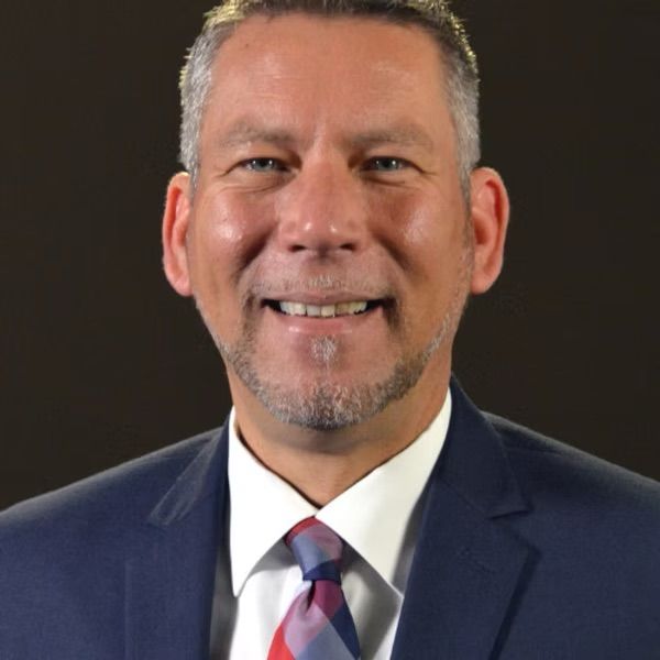 A man in a suit and tie is smiling for the camera