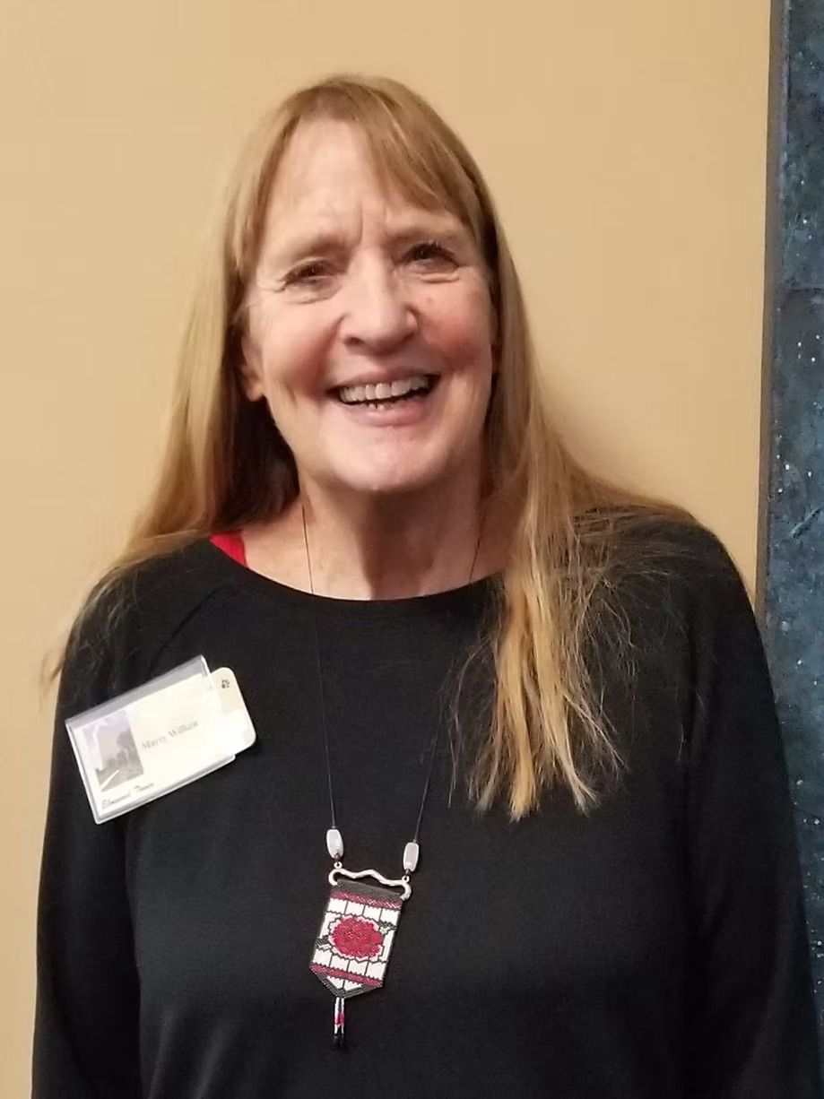 A woman wearing a black shirt and a name tag is smiling.