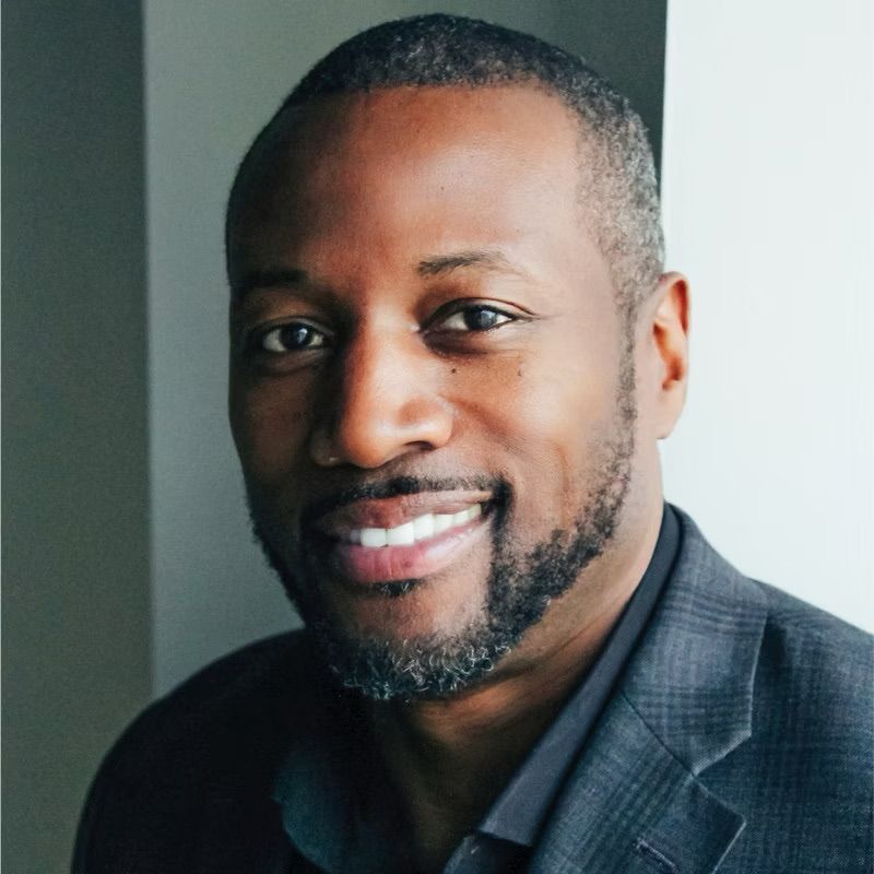 A man with a beard is smiling and wearing a suit
