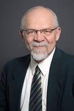 A man with a beard and glasses is wearing a suit and tie.