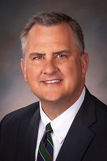 A man in a suit and tie is smiling for the camera.