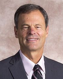 A man in a suit and tie is smiling for the camera.