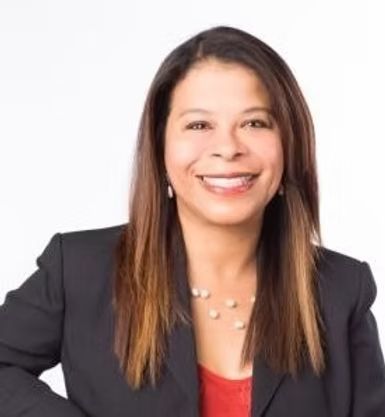 A woman in a black jacket and red shirt is smiling for the camera.