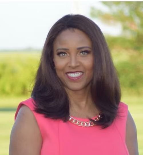 A woman in a pink dress is smiling for the camera