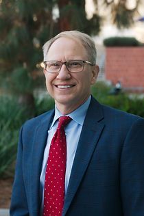 A man in a suit and tie is smiling for the camera.