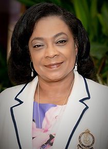 A woman in a white jacket and purple dress is smiling for the camera.