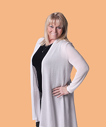 A woman wearing a white cardigan and a black top is standing with her hands on her hips.