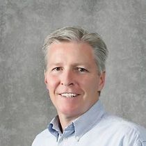 A man in a blue shirt is smiling for the camera.