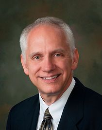 A man in a suit and tie is smiling for the camera.