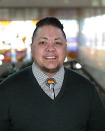 A man wearing a sweater and tie is smiling for the camera.