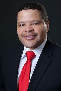 A man in a suit and red tie is smiling for the camera.