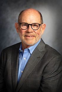 A man in a suit and glasses is smiling for the camera.