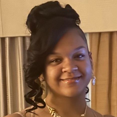 A woman wearing a necklace and earrings is smiling for the camera.