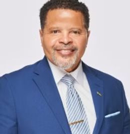 A man in a blue suit and tie is smiling for the camera.