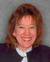 A woman in a black jacket and white shirt is smiling for the camera.