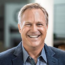A man in a suit and blue shirt is smiling for the camera.