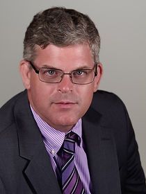 A man in a suit and tie is wearing glasses.