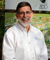 A man with a beard and glasses is wearing a white shirt and smiling.