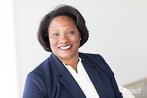 A woman in a blue jacket and white shirt is smiling for the camera.