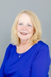 A woman in a blue shirt is smiling for the camera.