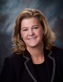 A woman in a black jacket is smiling for the camera.