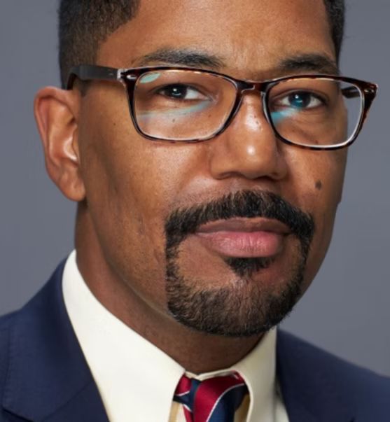 A man with a beard wearing glasses and a tie
