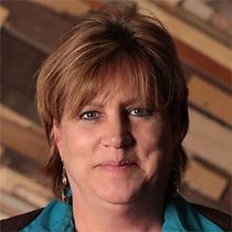 A close up of a woman 's face in front of a wooden wall.