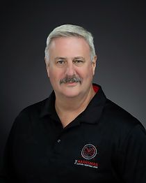 A man with a mustache is wearing a black polo shirt.