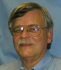 A man with glasses and a mustache is smiling for the camera.