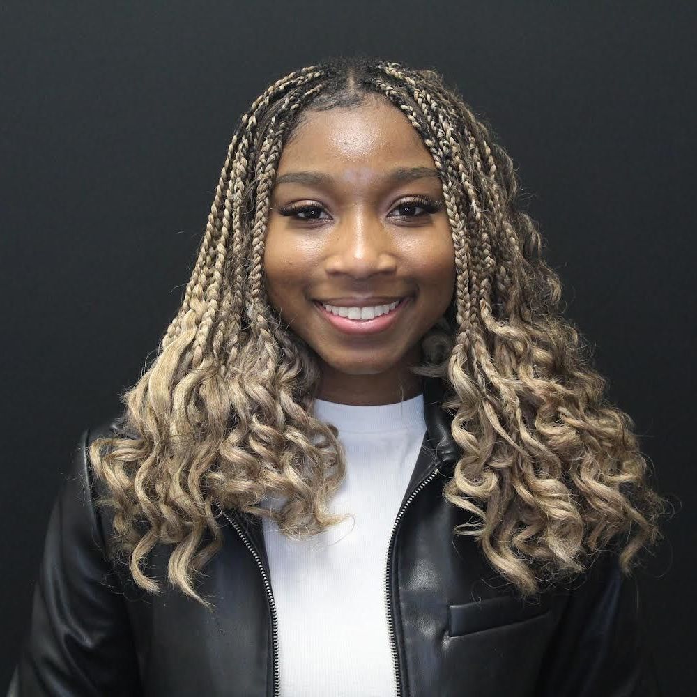 A woman with braids is wearing a black leather jacket and a white shirt.