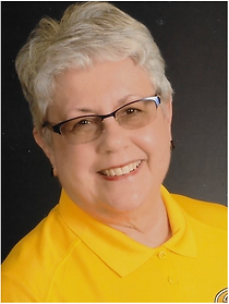 A woman wearing glasses and a yellow shirt is smiling for the camera.