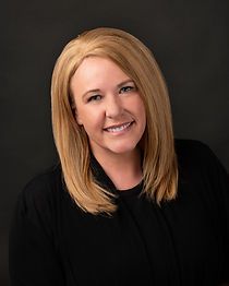 A woman with blonde hair is wearing a black shirt and smiling for the camera.