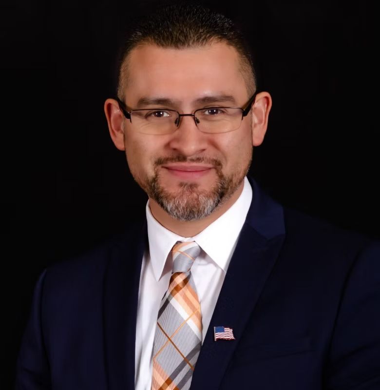 A man in a suit and tie with an american flag pin