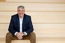 A man in a suit is sitting on a set of wooden stairs.