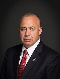 A man in a suit and tie is standing in front of a black background.