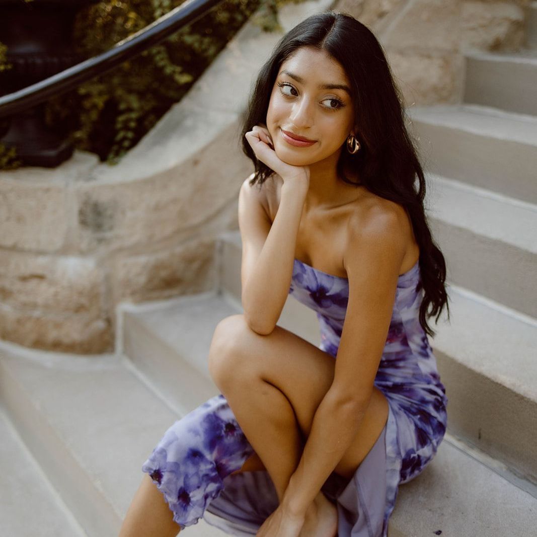 A woman in a purple dress sits on a set of stairs