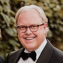 A man in a tuxedo and bow tie is smiling for the camera.