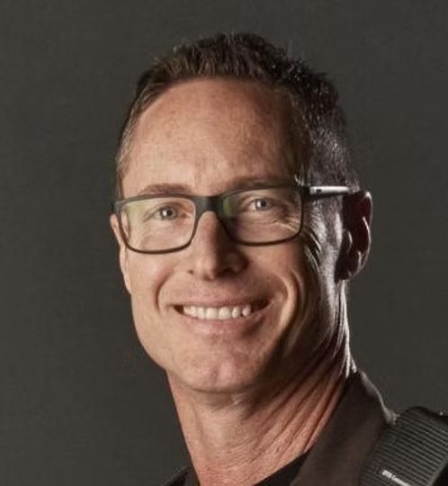 A man wearing glasses is smiling for the camera