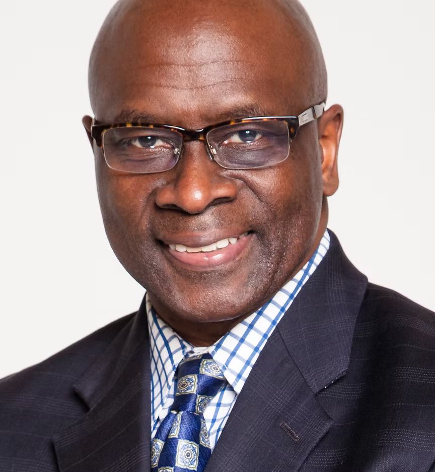 A man wearing glasses and a suit is smiling for the camera